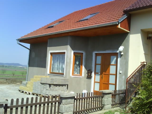 Střešní okna na novostavbě, šedý dům s dřevěnými okny a dveři, červená tašková střecha